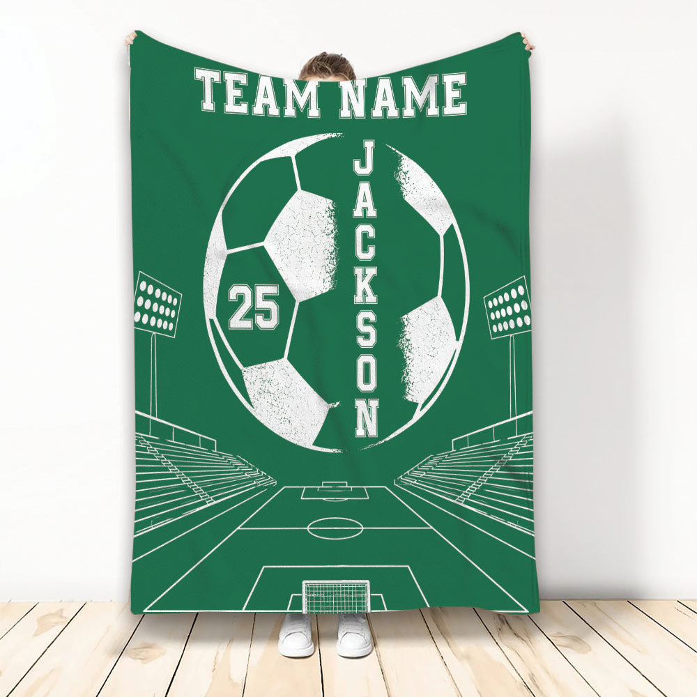 Green soccer blanket displayed upright with bold soccer ball artwork, stadium lights and goal field