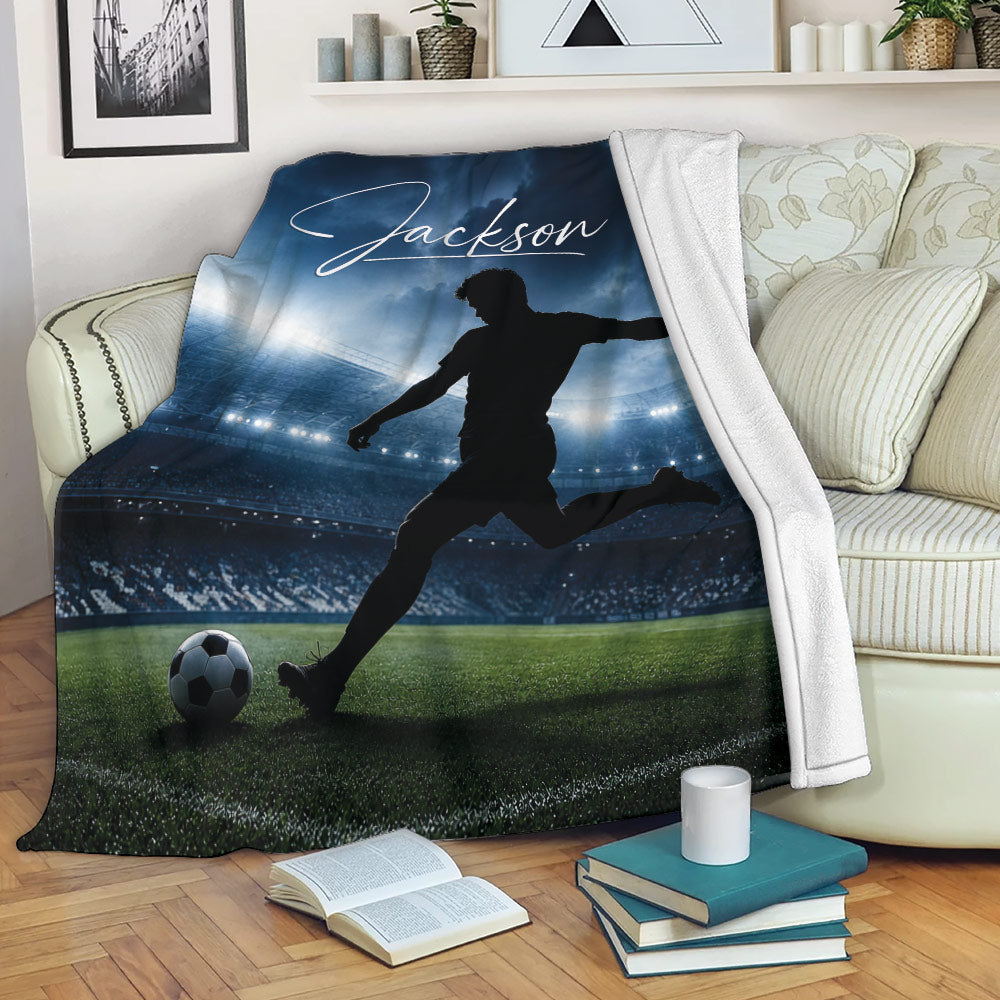 Soccer blanket draped over a sofa with stadium artwork, field, and silhouetted player