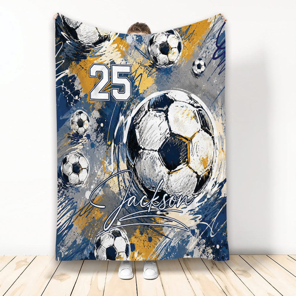 Soccer blanket with sketch-style soccer balls and bold navy, gold, gray, and white sports artwork