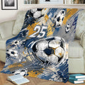 Soccer blanket draped over a sofa featuring dynamic navy, gold, gray, and white ball graphics