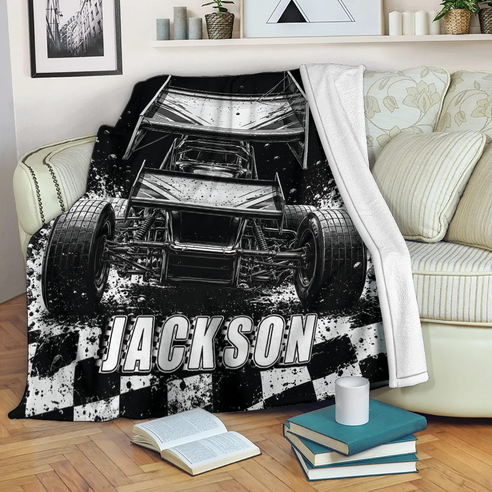 Dirt track racing blanket draped over a sofa, featuring a black and white sprint car and racing artwork