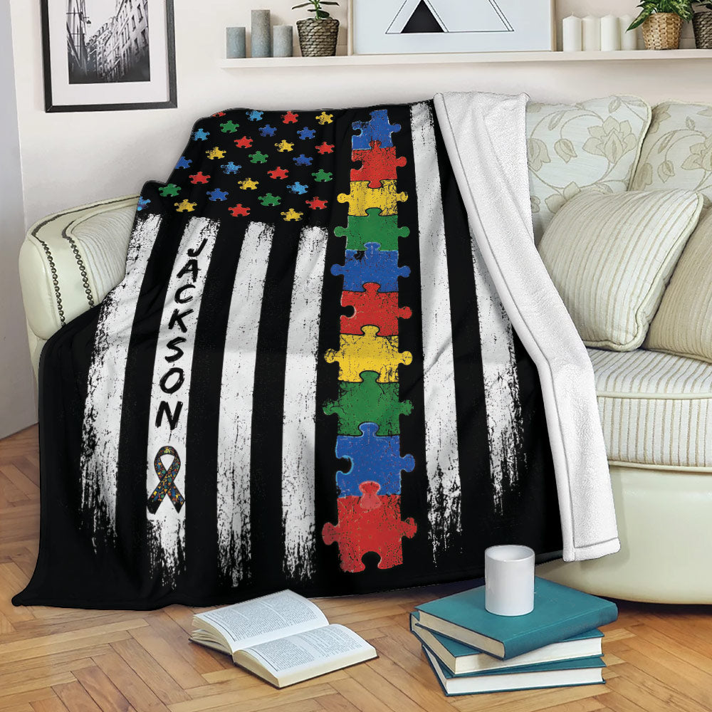 Autism awareness blanket draped over a sofa with colorful puzzle pieces and bold black and white stripes