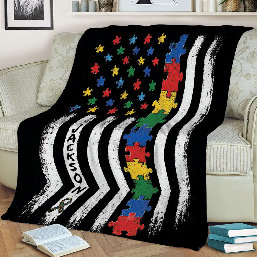 Autism awareness throw blanket displayed on a couch with colorful puzzle pieces and graphic striped artwork