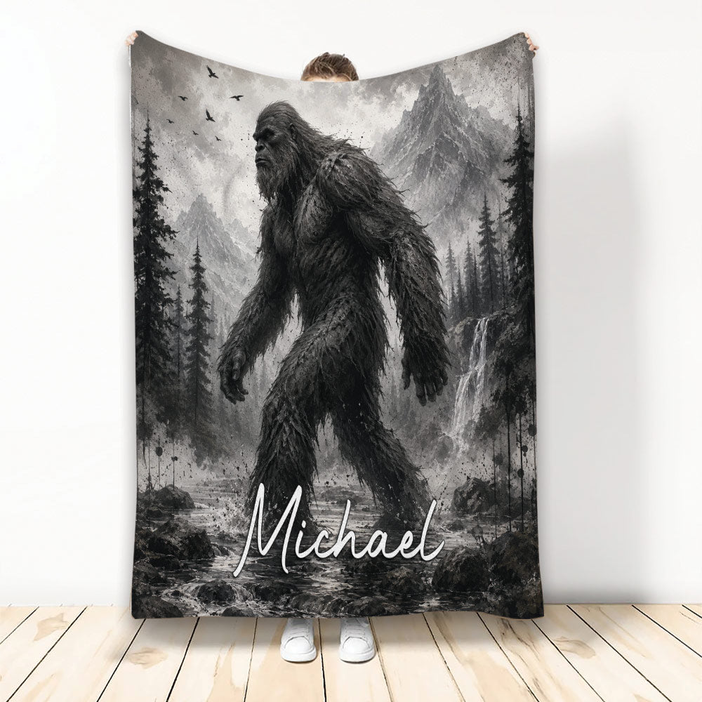 Bigfoot throw blanket displayed vertically with grayscale mountain, forest, waterfall, and wilderness artwork