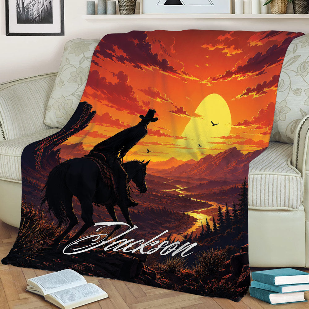 Cowboy blanket displayed on a couch with horse and rider, glowing sun, rugged mountains, and western scenery