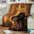 Cowboy throw blanket draped over a couch with western hat and boots against rustic wood artwork