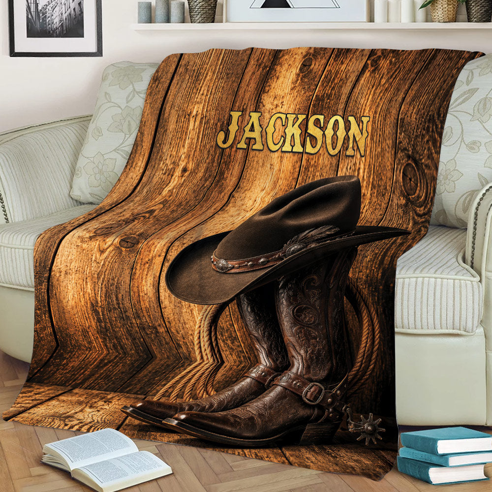 Cowboy throw blanket draped over a couch with western hat and boots against rustic wood artwork