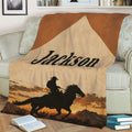 Cowboy throw blanket displayed on a couch with horseback rider silhouette and rustic sunset scenery