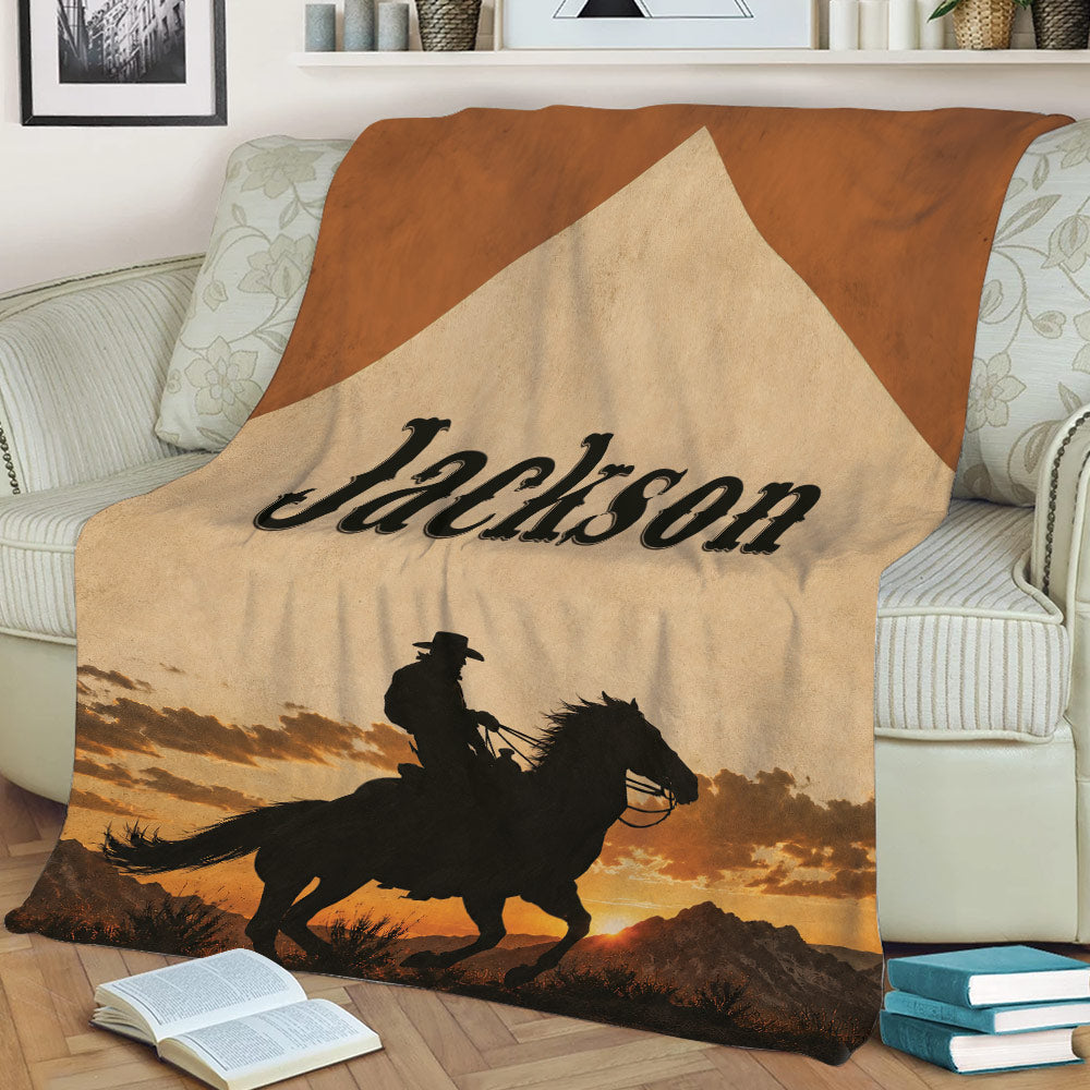 Cowboy throw blanket displayed on a couch with horseback rider silhouette and rustic sunset scenery
