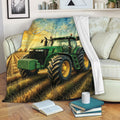 Tractor throw blanket draped over a sofa with a green tractor working in a sunlit farm field