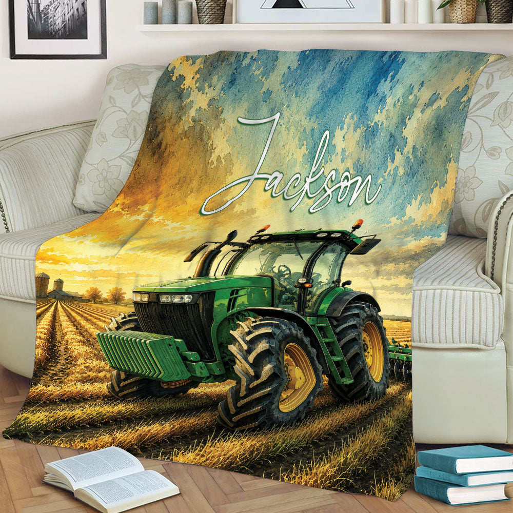 Farm tractor blanket styled on a sofa, featuring a green tractor, harvested field, and rustic landscape artwork