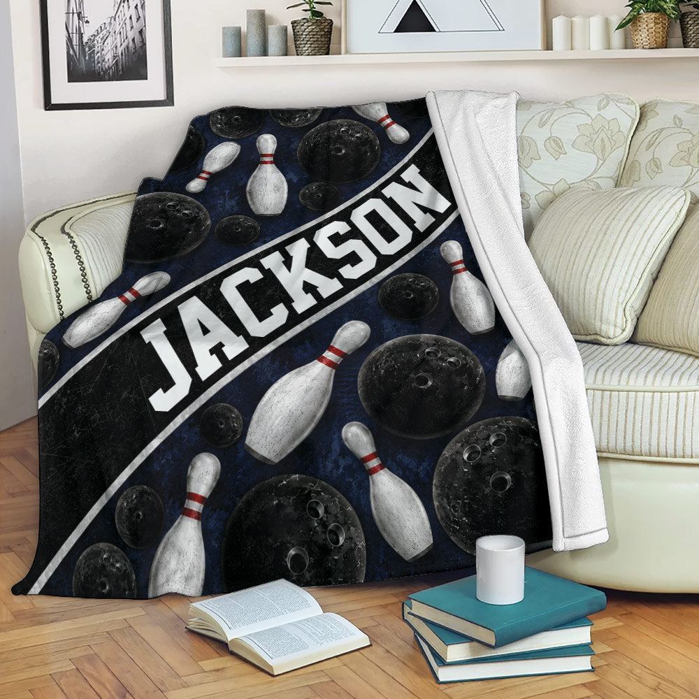 Bowling blanket draped over a sofa with black balls, white pins, and navy blue artwork
