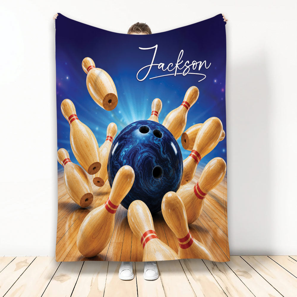 Custom bowling blanket featuring a blue bowling ball striking wooden pins on a glowing lane