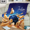 Bowling blanket displayed on a couch with dynamic bowling ball and pin artwork