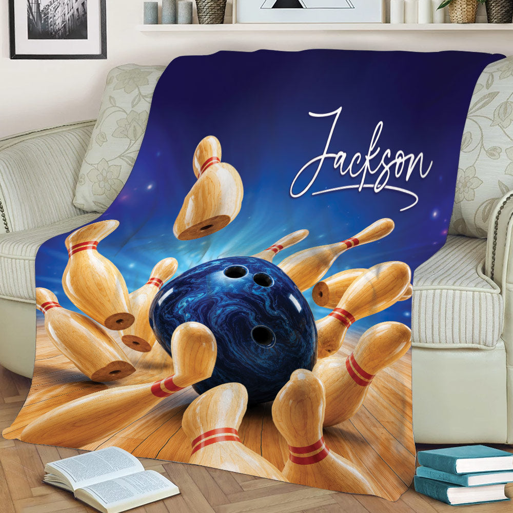 Bowling blanket displayed on a couch with dynamic bowling ball and pin artwork