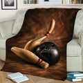 Bowling throw blanket displayed across a couch with wooden pins and a black ball in detailed artwork