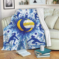 Blue and yellow volleyball throw blanket displayed across a sofa with energetic player silhouettes