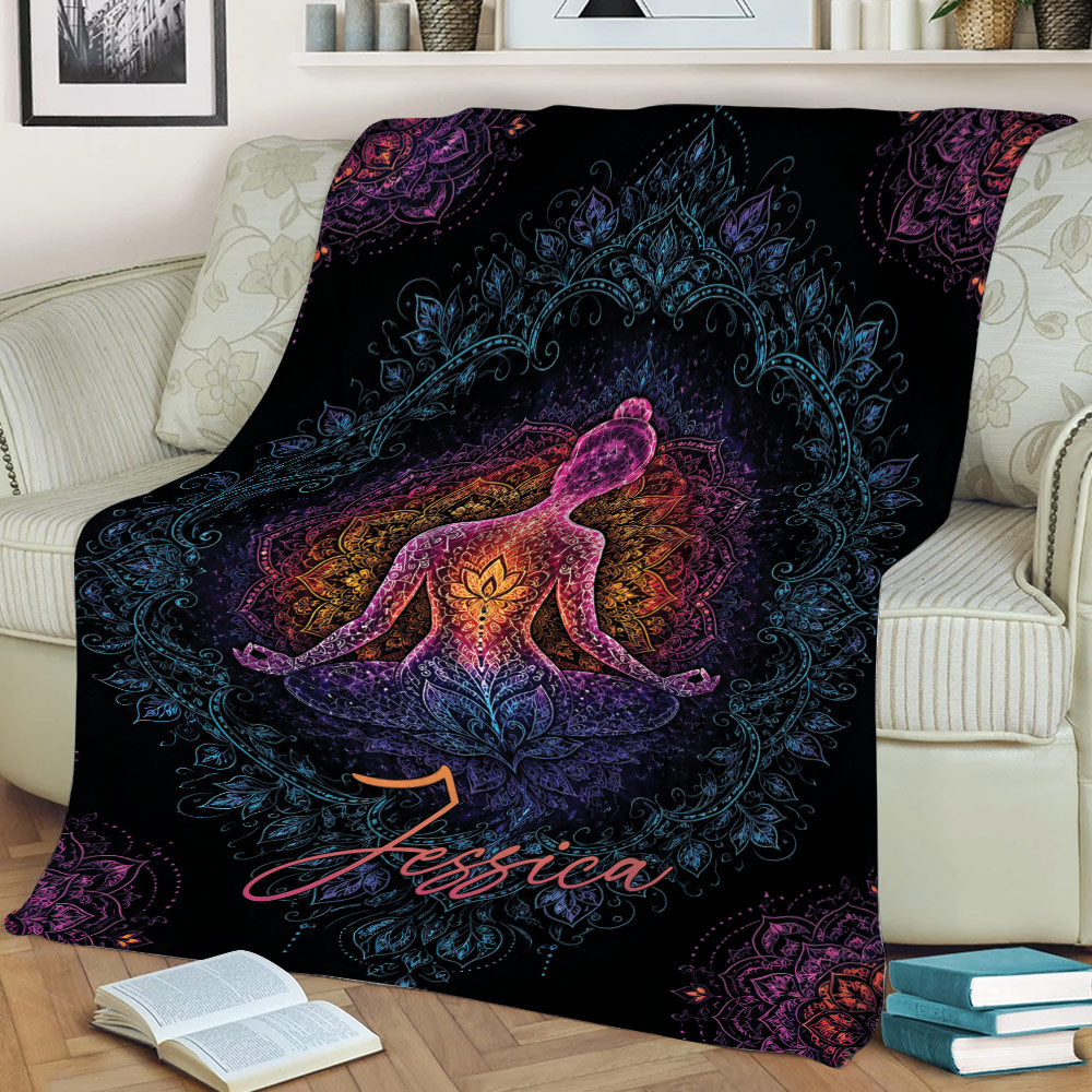 Vibrant meditating figure and floral mandala yoga blanket on a couch