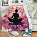 Yoga blanket displayed on a sofa with a meditating figure, pink lotus petals, and artistic watercolor textures