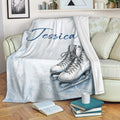 Ice skating throw blanket draped over a sofa with illustrated skates and pale blue snowflake artwork