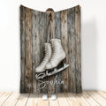 Ice skating throw blanket displayed with white figure skates, snowflakes, and rustic wood artwork