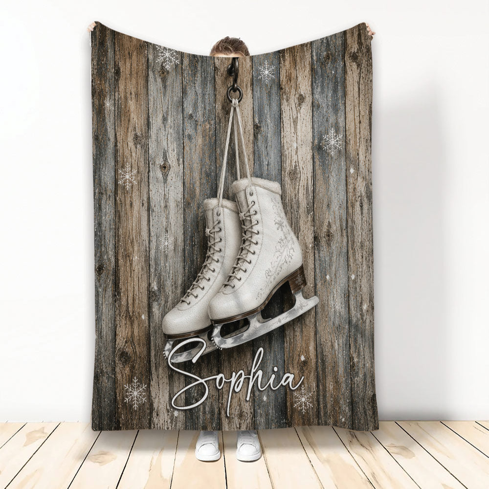 Ice skating throw blanket displayed with white figure skates, snowflakes, and rustic wood artwork