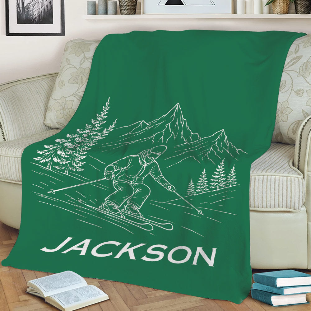 Green skiing throw blanket on a sofa with skier, mountain, and evergreen artwork