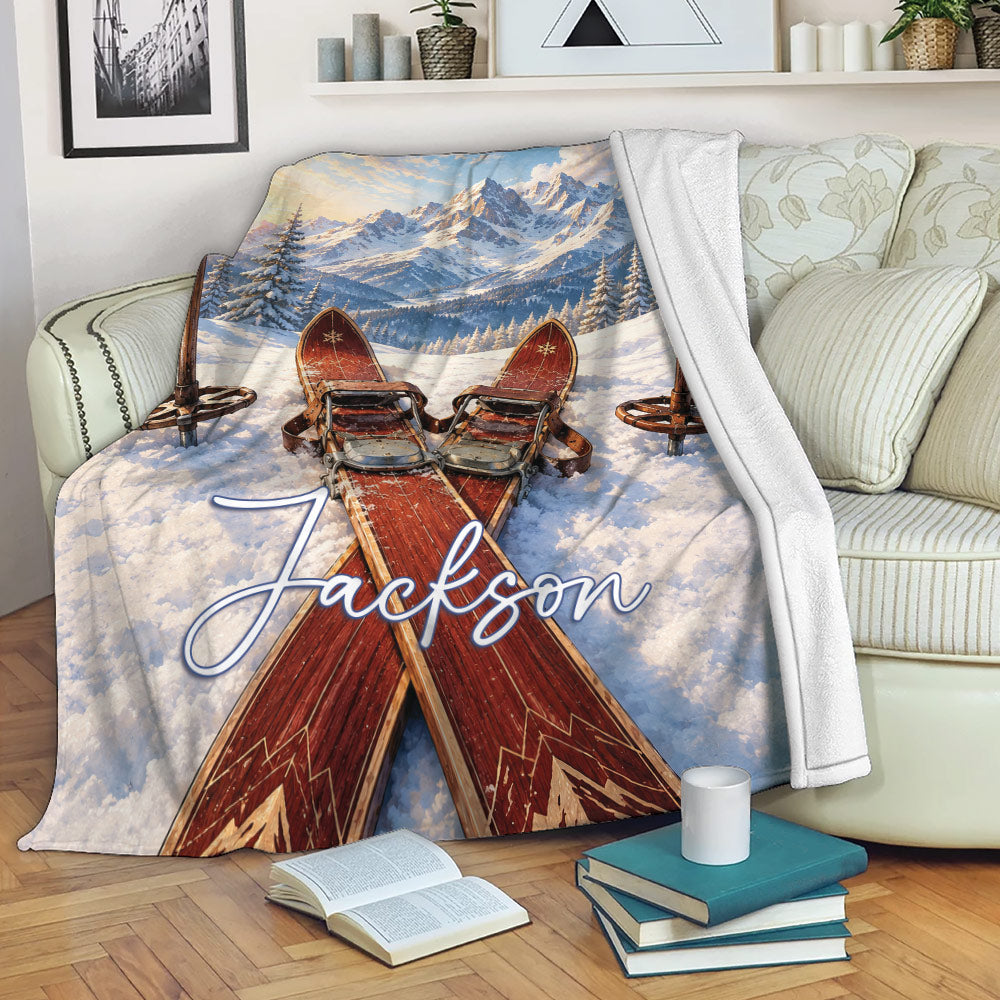 Skiing blanket displayed on a sofa with skis, snowy mountains, and cozy winter scenery