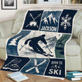 Skiing blanket draped over a couch featuring a skier, snowy mountain scene, ski boots, and blue winter artwork