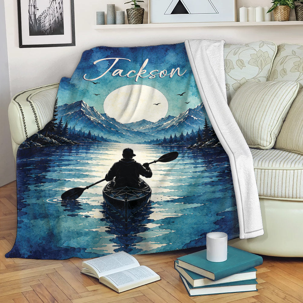 Kayak blanket draped over a sofa with mountain lake artwork, moonlit scenery, and a paddler on the water