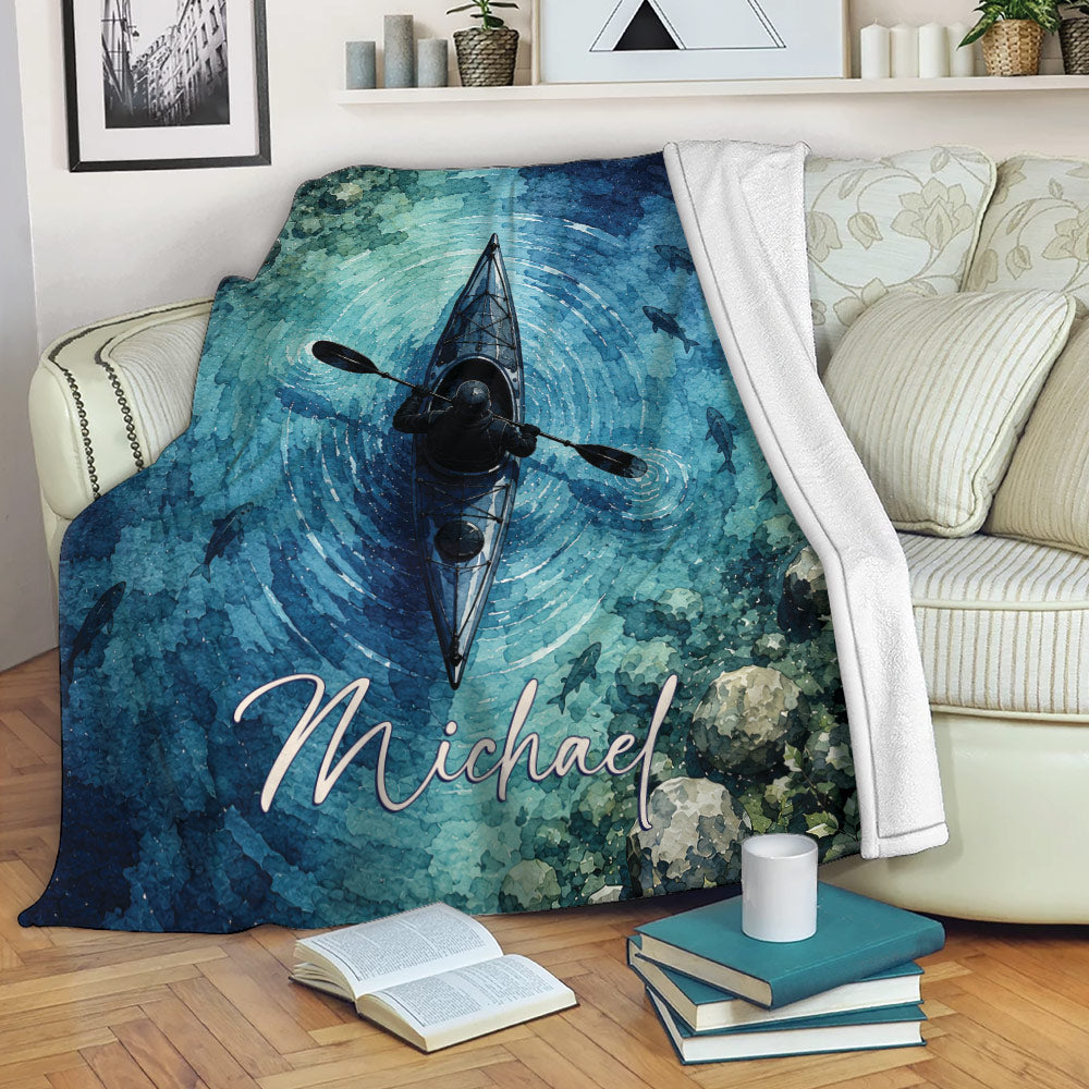 Kayak throw blanket displayed on a sofa with blue water artwork, fish, and a paddler