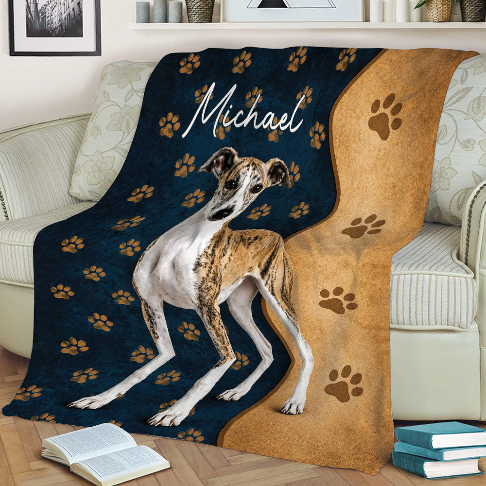 Whippet blanket styled on a couch with navy paw prints, tan accents, and dog artwork