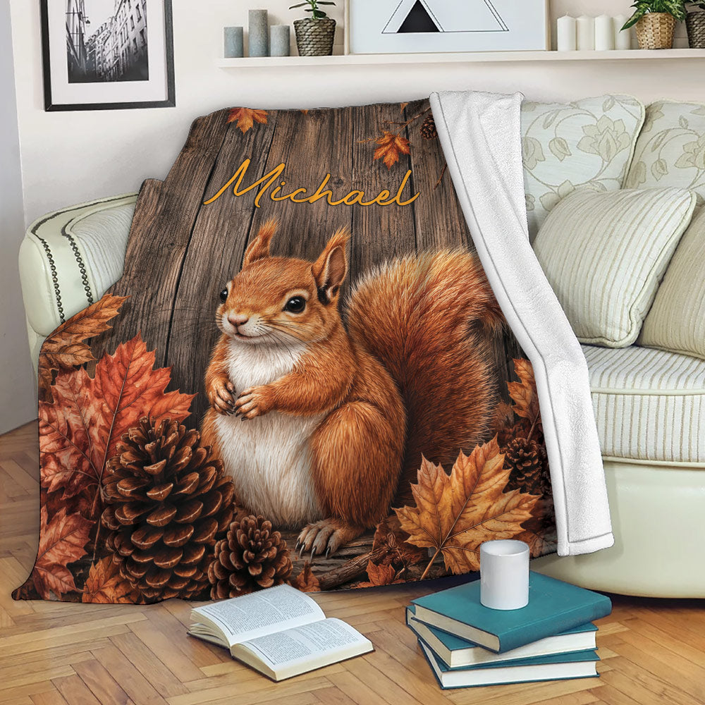 Squirrel throw blanket with autumn woodland artwork draped over a sofa beside books