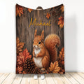 Squirrel blanket with rustic wood background, autumn leaves, and pinecones shown hanging in a room