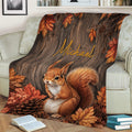 Rustic squirrel blanket with fall leaves and pinecones arranged across an armchair