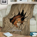 Close lifestyle view of a squirrel throw blanket draped across a sofa with woodland artwork