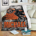 Motocross blanket draped over a sofa with dirt bike rider artwork in an orange and distressed black design