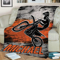 Motocross throw blanket displayed on a couch with dynamic dirt bike rider and rugged orange graphic design