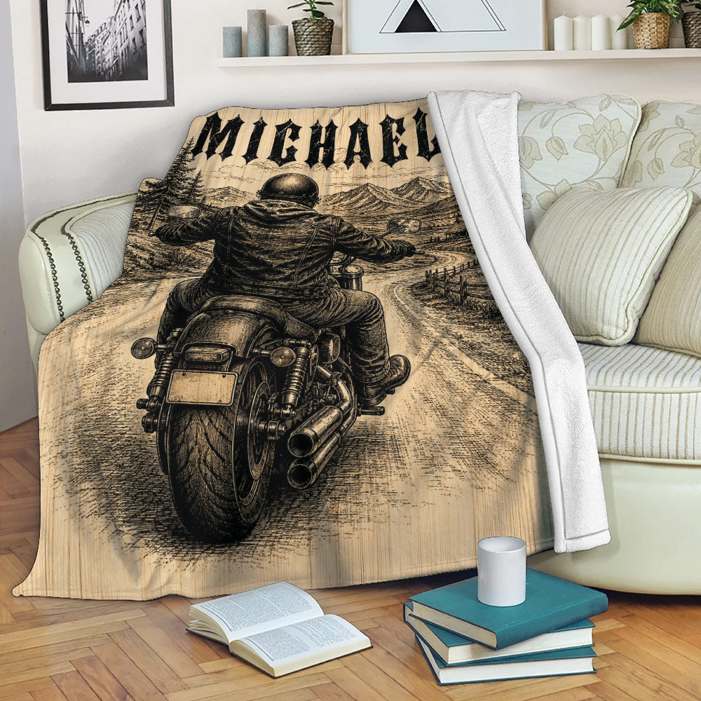 Biker throw blanket displayed on a sofa with motorcycle rider and mountain road artwork