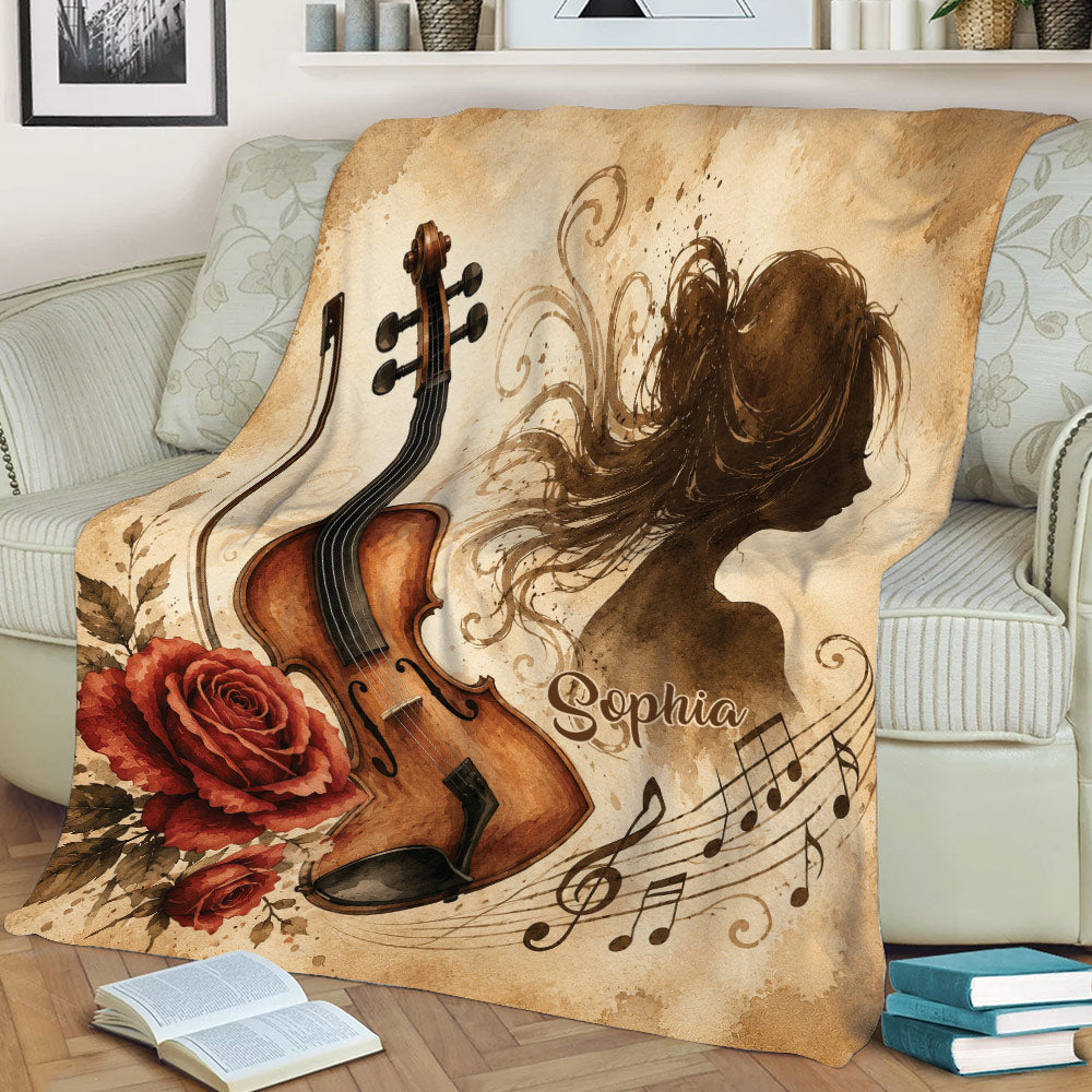 Decorative violin blanket displayed on a sofa with a musician silhouette, roses, and flowing musical notes