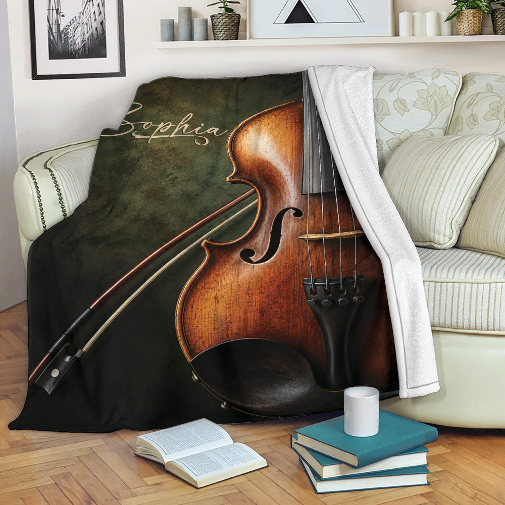 Violin throw blanket draped over a sofa with books and a cup in a cozy living room