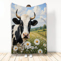 Cow blanket featuring a black and white horned cow in a daisy meadow beneath a blue sky
