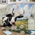 Cow blanket draped across a sofa with a horned cow, countryside field and daisy meadow scene