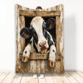 Cow throw blanket featuring a black and white cow peeking through a rustic wooden barn window