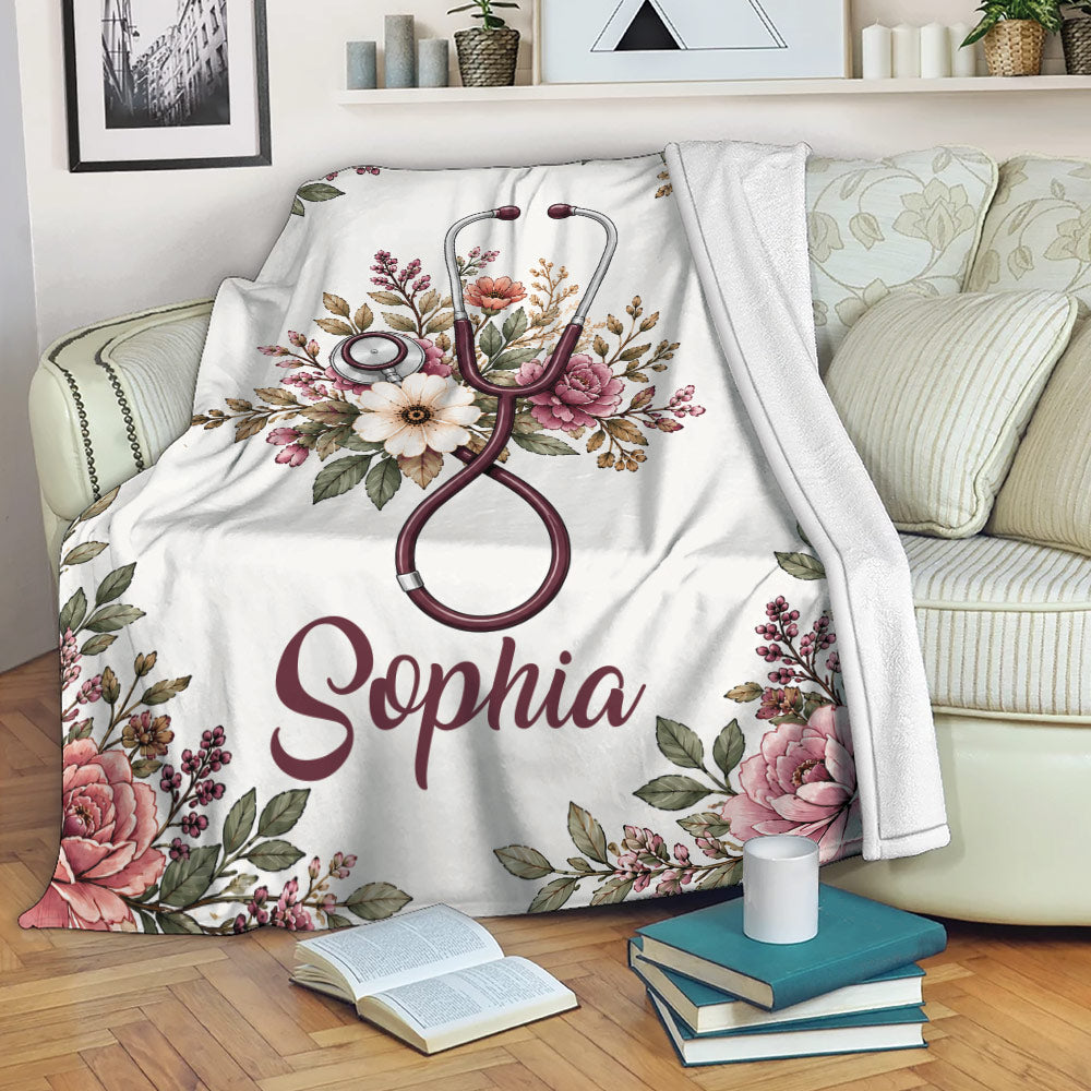 Floral nurse blanket displayed on a sofa with stethoscope artwork and botanical accents