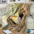 Close lifestyle view of a watercolor cockatiel blanket draped over a living room sofa