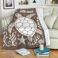 Brown sea turtle blanket draped over a sofa with coastal artwork and a cozy reading area