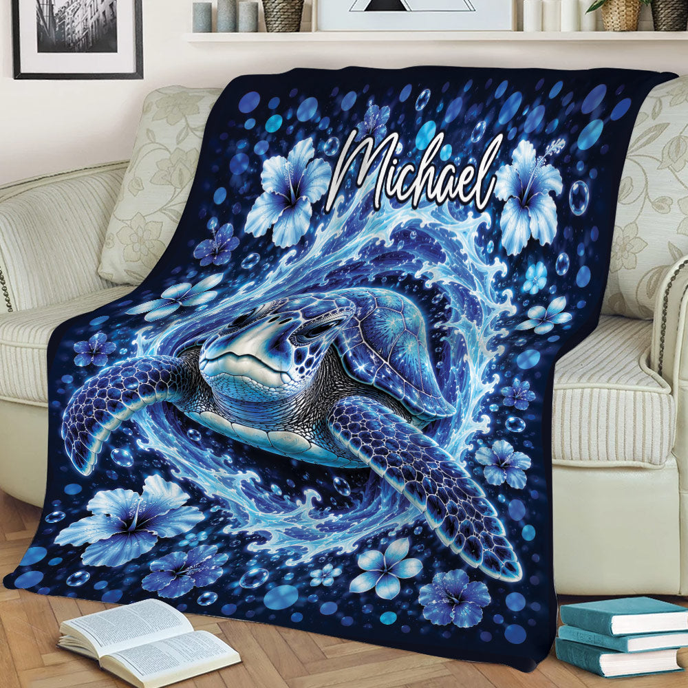 Ocean turtle blanket draped over a couch with swirling waves, bubbles, and blue hibiscus flowers