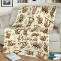 Sloth throw blanket displayed on a couch with repeating sloth and branch artwork