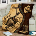 Rustic rodeo throw blanket on a couch featuring bull riding artwork, desert landscape, cowboy hat, and boots